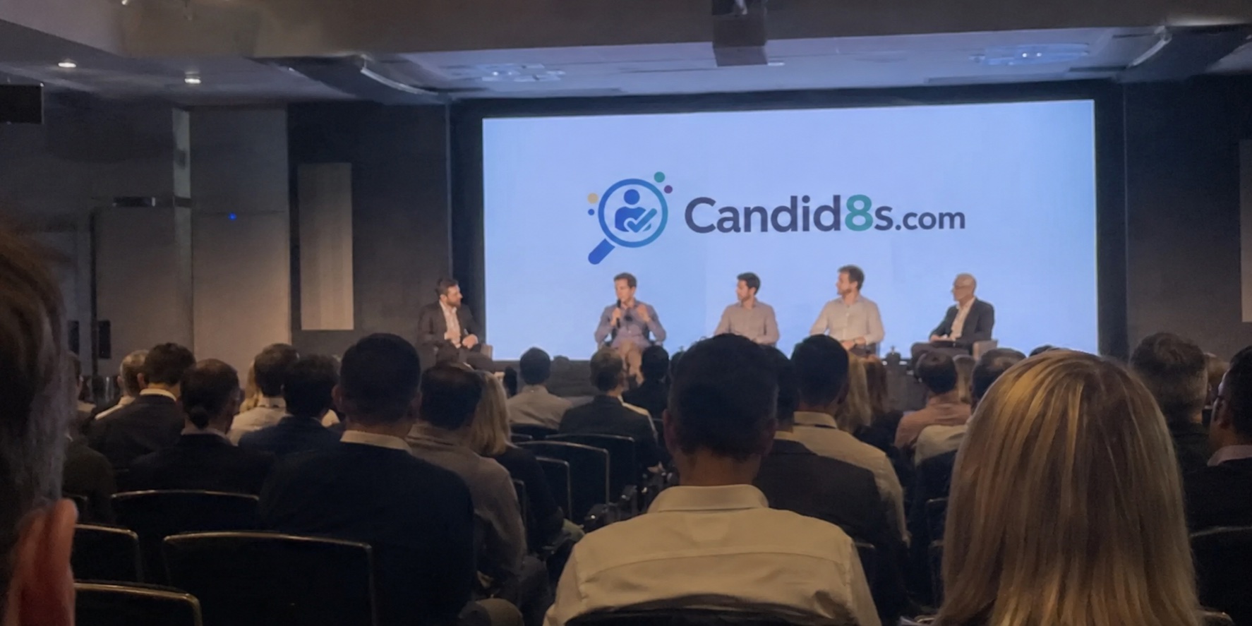 A Candid8 panel discussion in front of a full room